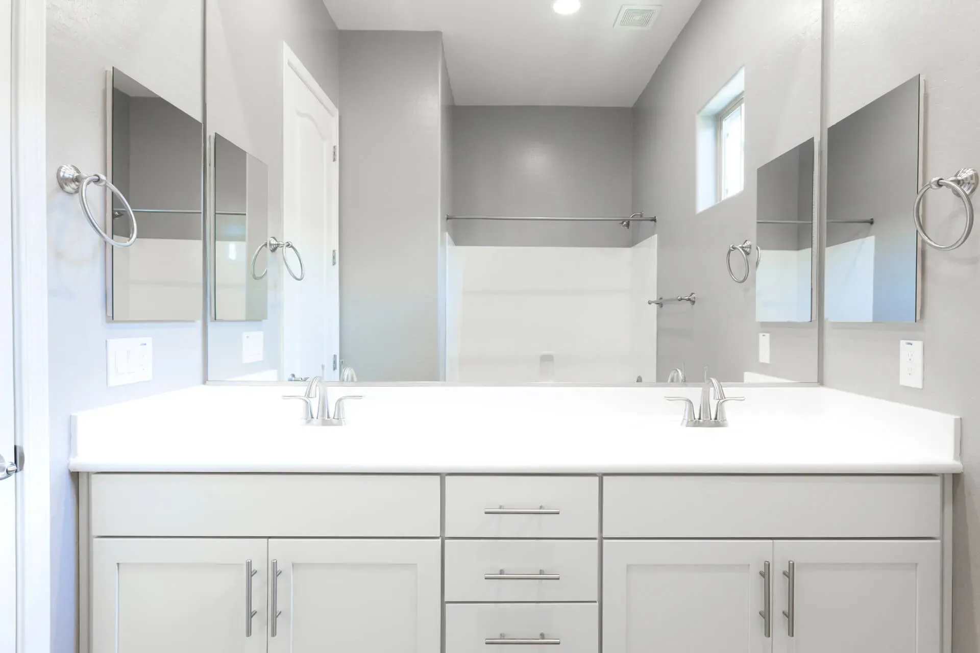 Modern bathroom with light gray walls, a double vanity with white countertop, and square mirrors above each sink. Bright and minimalist design.
