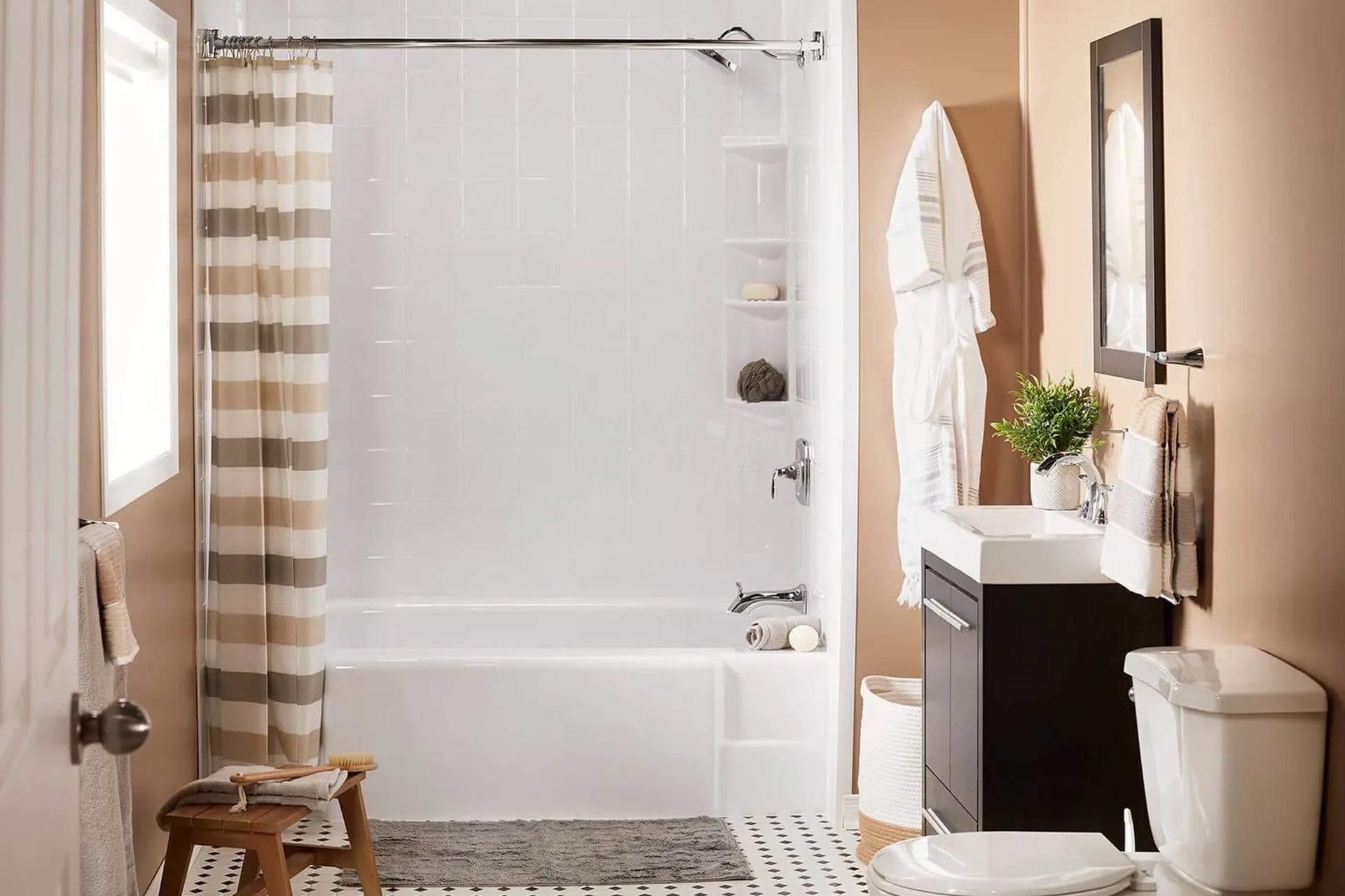 Modern bathroom with a white bathtub and striped shower curtain. Beige walls, dark vanity with plant, white towels, and a toilet.
