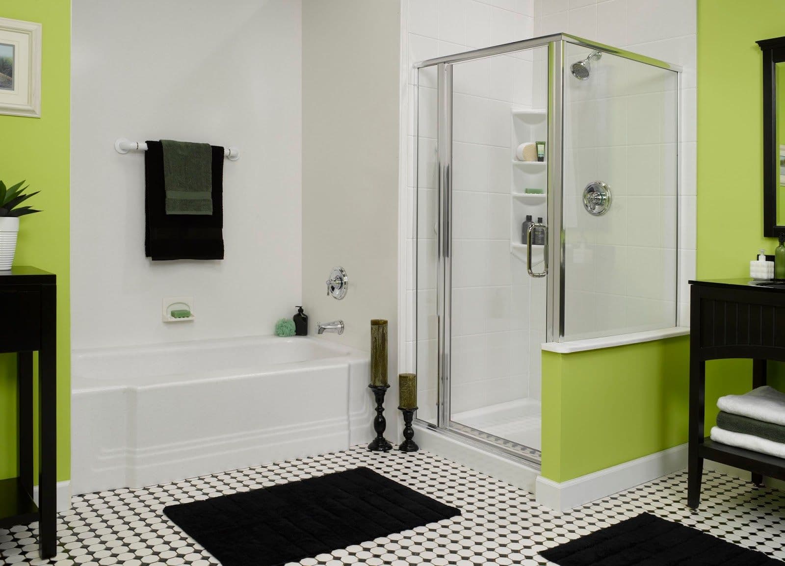 Modern bathroom with a white tub and glass shower. Lime green and black accents, including towels and candles, create a fresh, elegant look.