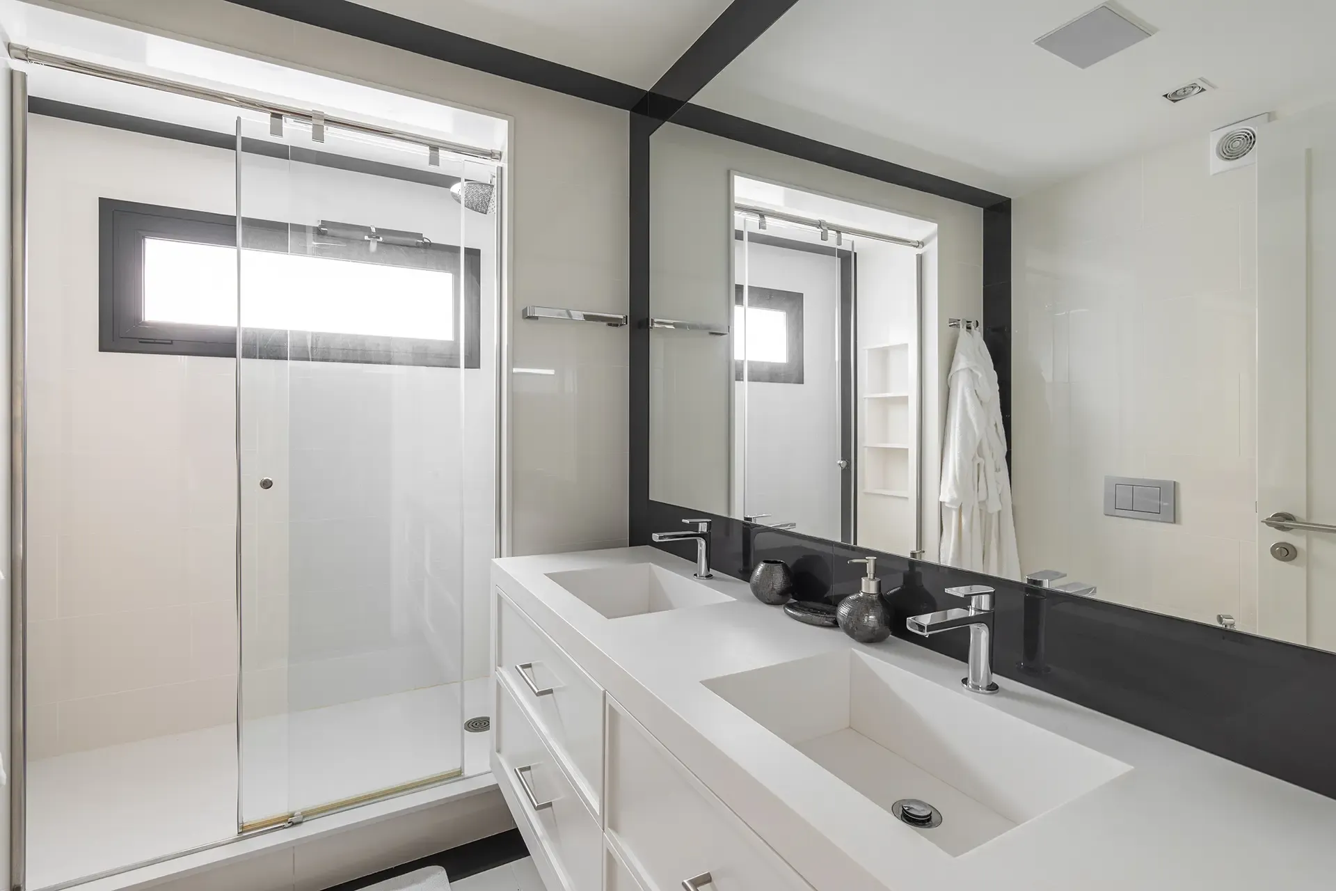 Modern bathroom with a double-sink vanity and large mirror. Glass-enclosed shower on the left.