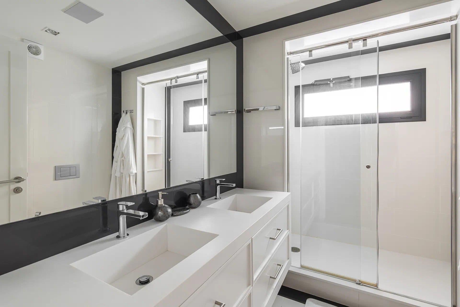 Modern bathroom with a double-sink vanity and large mirror. Glass-enclosed shower on the right.
