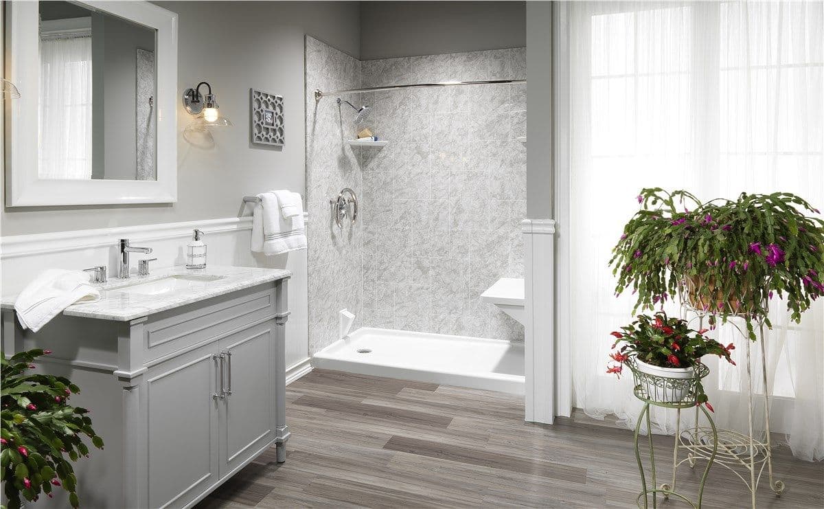 A light gray bathroom with a walk-in shower with light-gray marble-patterned walls and built-in bench seat.