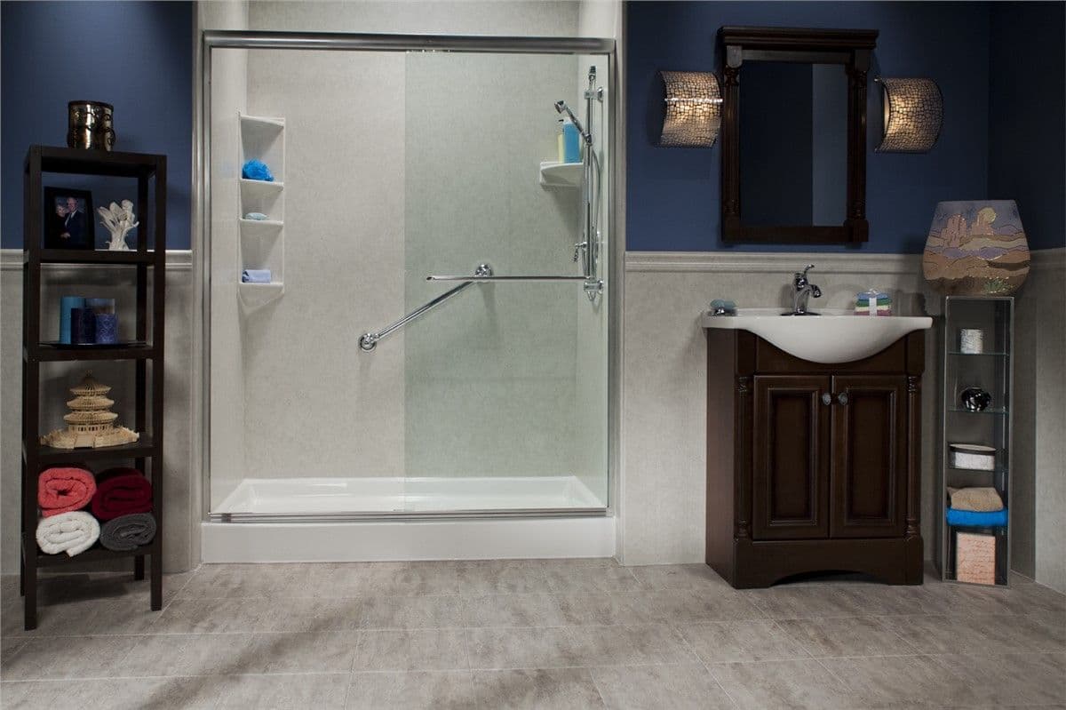 Modern bathroom with a spacious glass shower, blue walls, and dark wood accents. A vanity with a mirror on the right, and neatly organized shelves on the left.